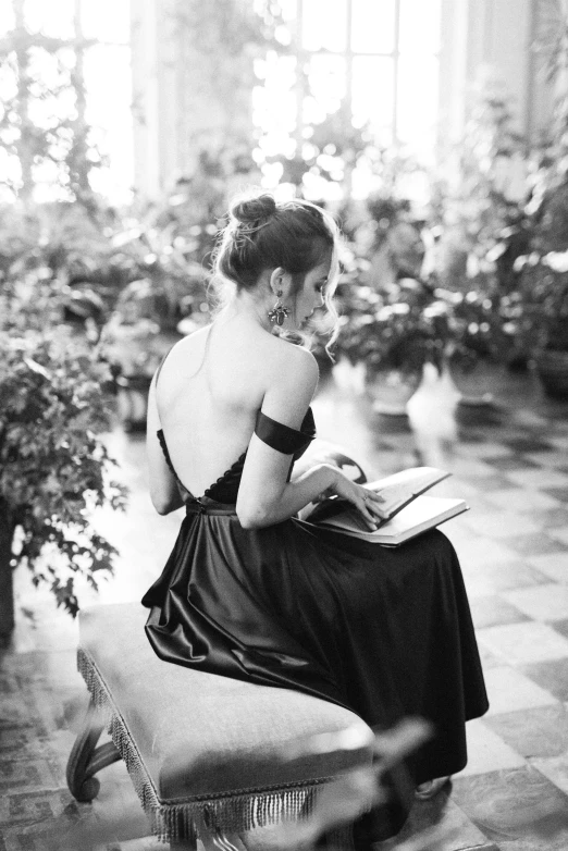 a woman sitting on a bench reading a book, a black and white photo, tumblr, aestheticism, open back dress, elegant glamourous cosplay, 🌺 cgsociety, young woman