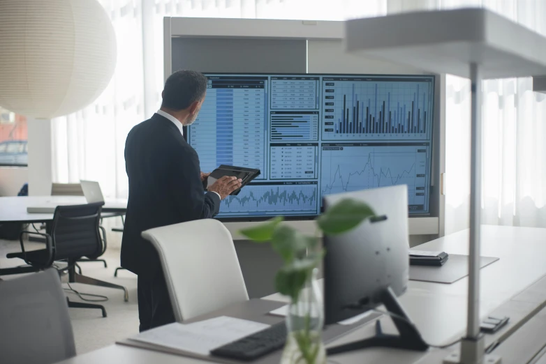 a man standing in front of a computer monitor, analytical art, foster and partners, axsens, markets, from a movie scene