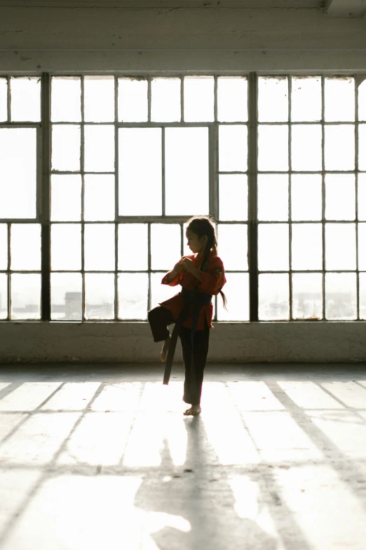 a little girl that is standing in front of a window, inspired by Liao Chi-chun, unsplash, arabesque, karate kick, standing in a large empty hall, back - lit, chicago