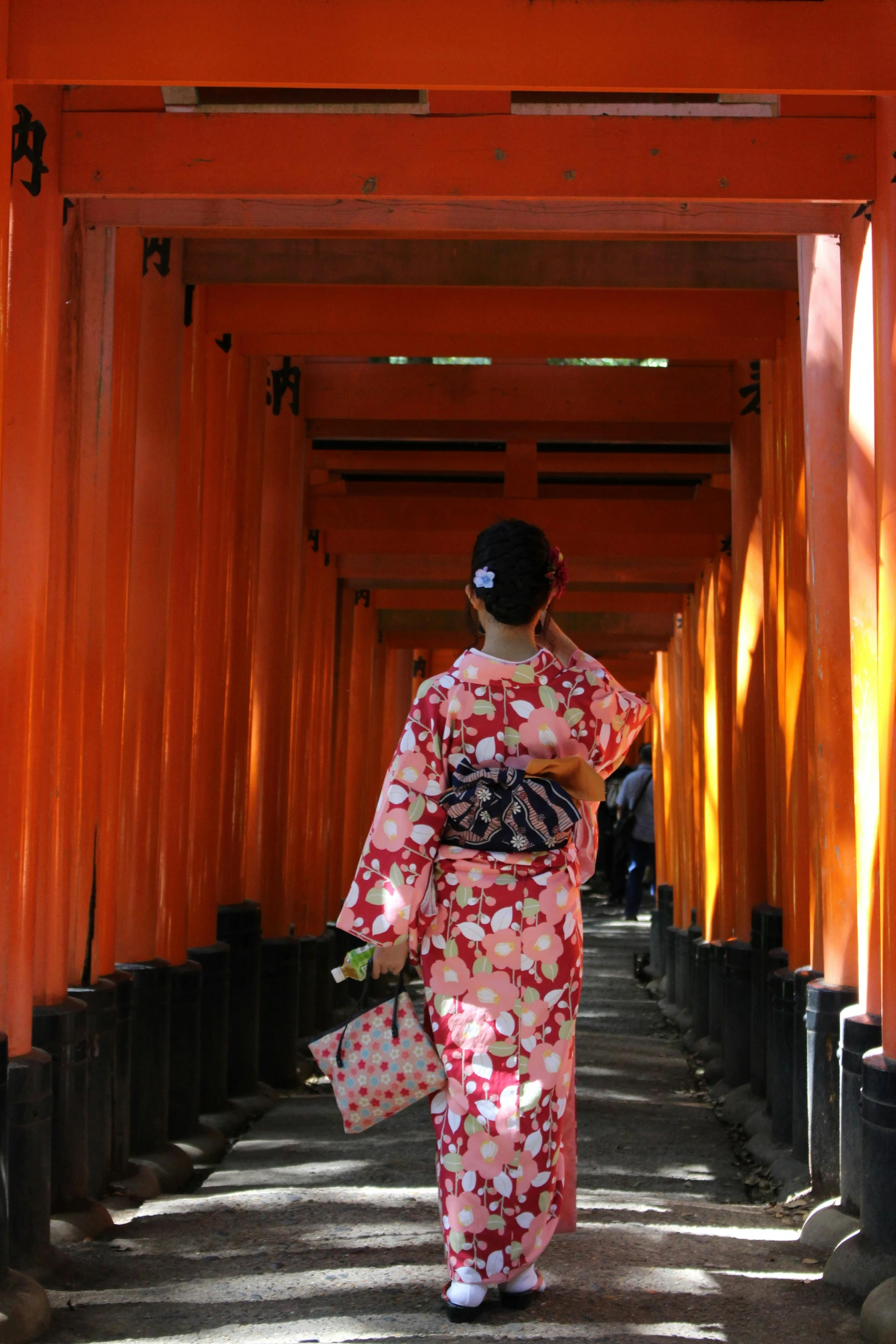 a woman in a kimono walking through a tunnel, orange red black white, wearing authentic attire, orange metal ears, taken in the late 2010s