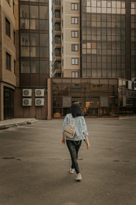 a woman walking down a street past tall buildings, pexels contest winner, hyperrealism, denim, low quality photo, basic photo, exploring abandoned city