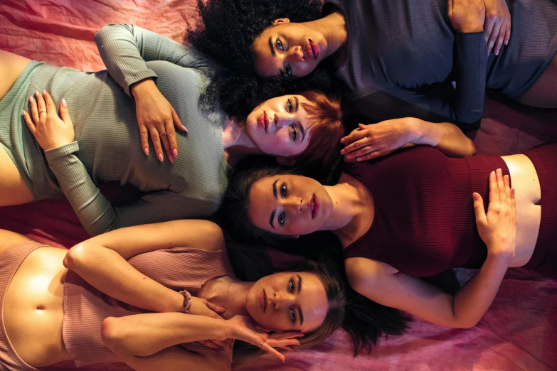 a group of women laying on top of a bed, inspired by Nan Goldin, trending on pexels, figuration libre, portrait 8 k, circle, nathalie emmanuel, confident looking