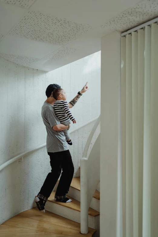 a man standing at the top of a set of stairs, inspired by Leandro Erlich, pexels contest winner, light and space, father holds child in the hand, tyler edlin and natasha tan, dwell, looking around a corner