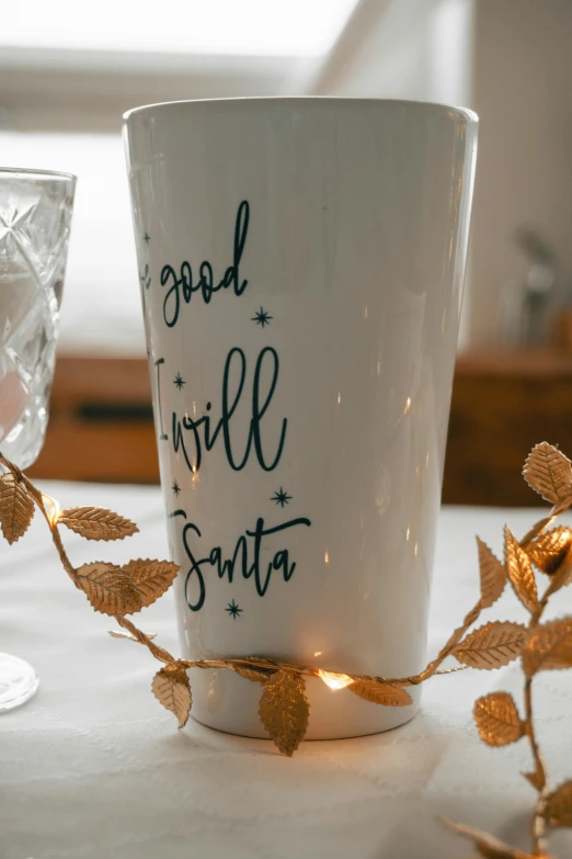 a white coffee cup sitting on top of a table, fairy lights, engraved, large tall, seasonal