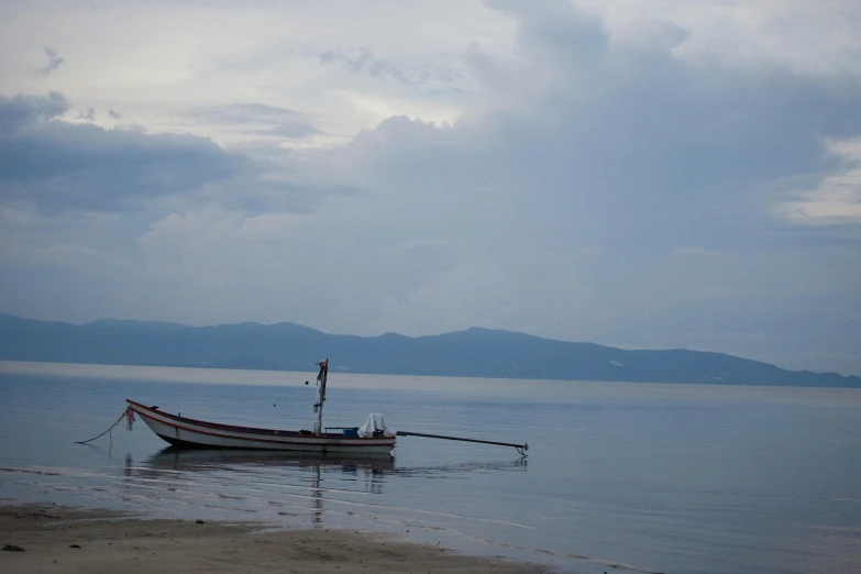 a boat sitting on top of a beach next to the ocean, inspired by Edwin Georgi, sumatraism, split near the left, on a cloudy day, lerapi, early evening