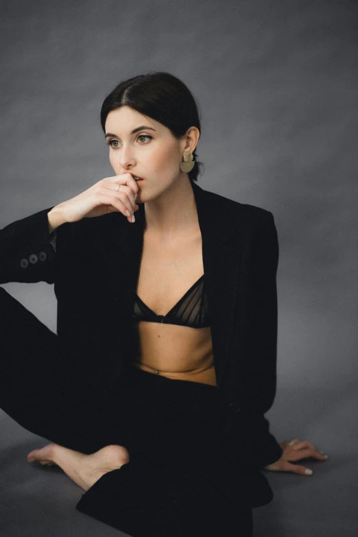 a woman in a black suit sitting on the floor, inspired by Hedi Xandt, trending on pexels, minimalism, bralette, laetitia casta, exposed midriff, woman with black hair