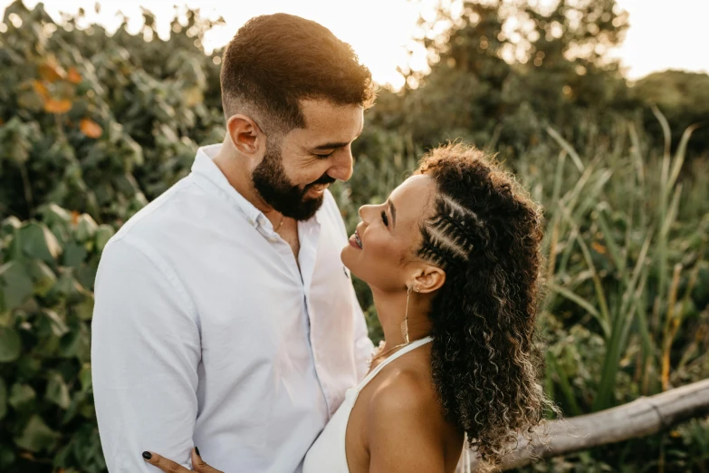 a man and woman standing next to each other in a field, pexels contest winner, with textured hair and skin, flirting smiling, hispanic, profile image