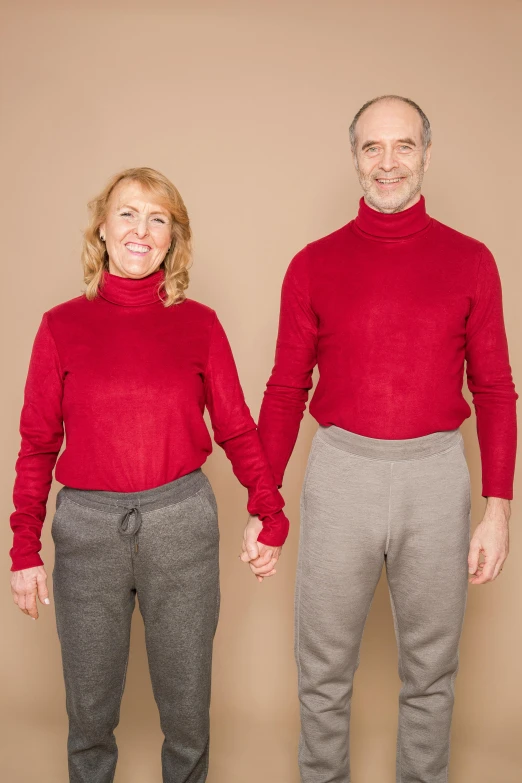 a man and a woman standing next to each other, red sweater and gray pants, highly symmetric body parts, aging, non-binary