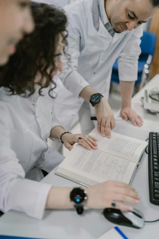 a couple of people that are sitting in front of a computer, lab coat, holding a book, high-quality photo, gif