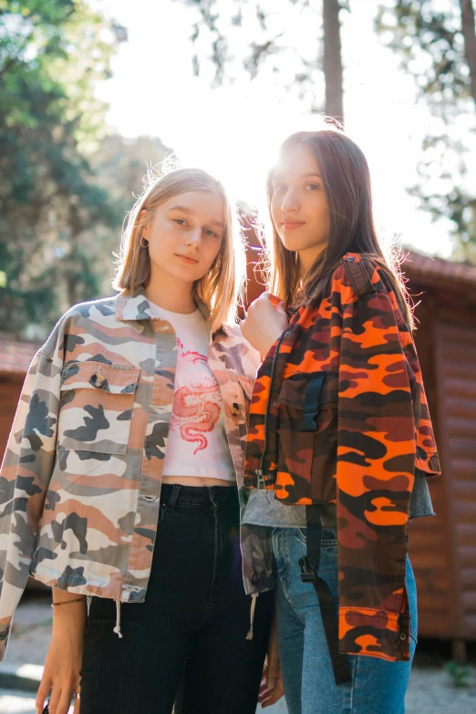 two women standing next to each other in front of a cabin, inspired by Elsa Bleda, trending on unsplash, graffiti, camouflage uniform, cropped shirt with jacket, 🎀 🍓 🧚, teenage girl