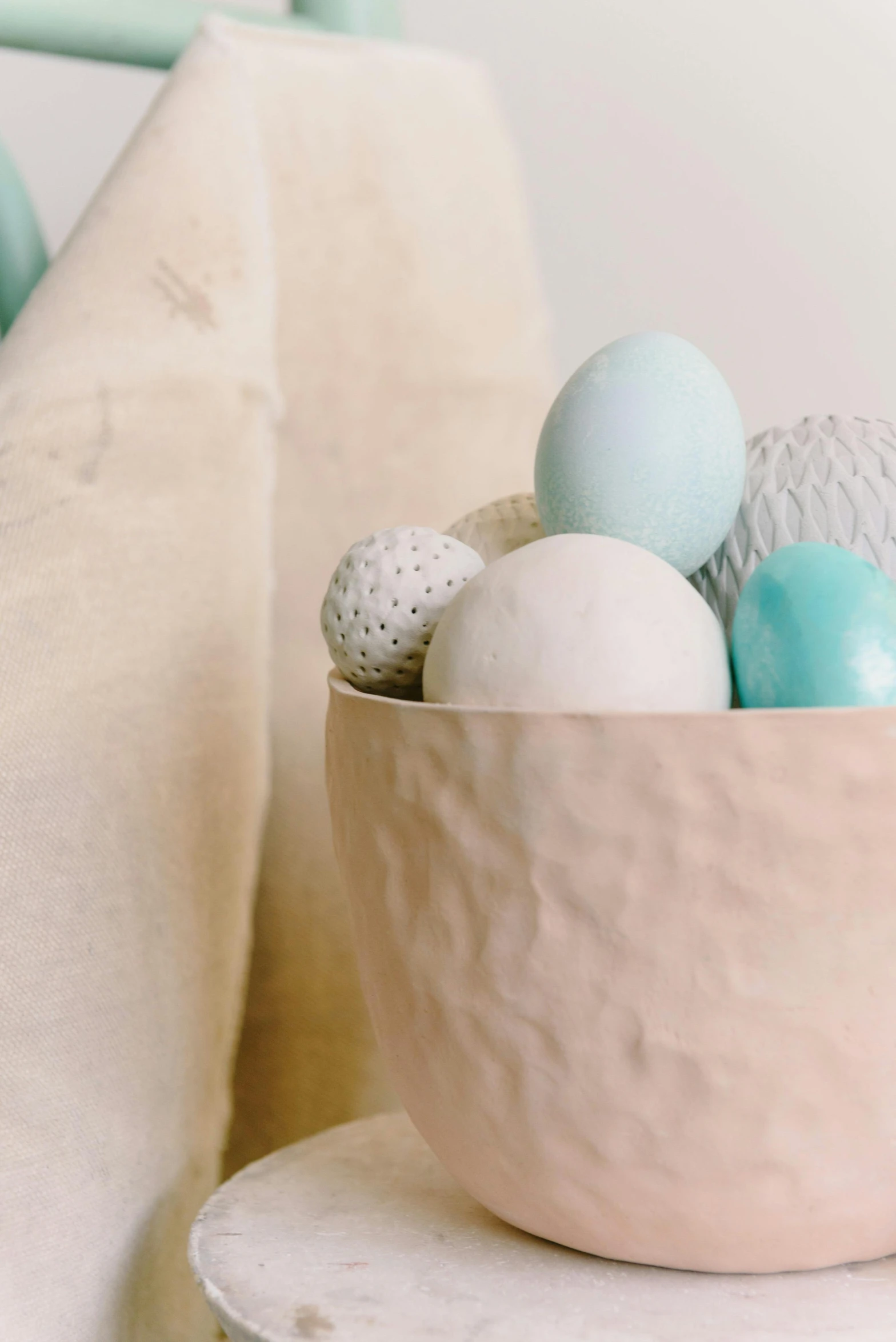 a bowl filled with eggs sitting on top of a table, pastel color theme, curated collections, paper decoration, up-close