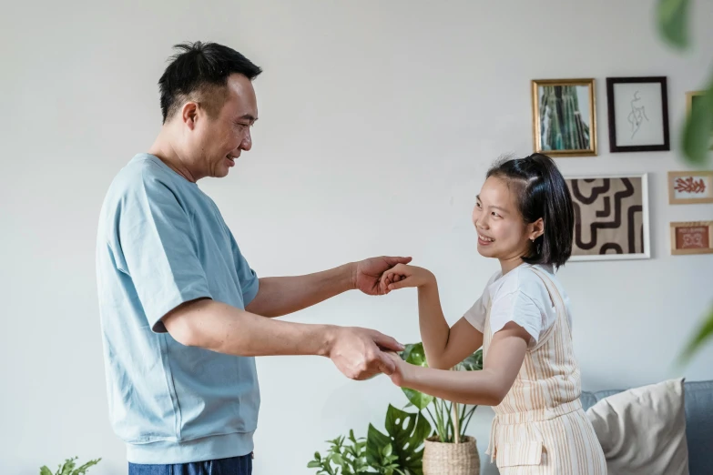 a man standing next to a little girl in a living room, pexels contest winner, chinese ribbon dance, partially cupping her hands, profile image, acupuncture treatment