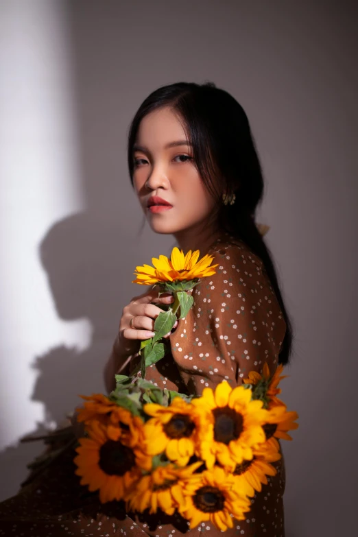 a woman is holding a bunch of sunflowers, an album cover, inspired by Xie Sun, trending on pexels, portrait lighting, vietnamese woman, indoor picture, dao trong le