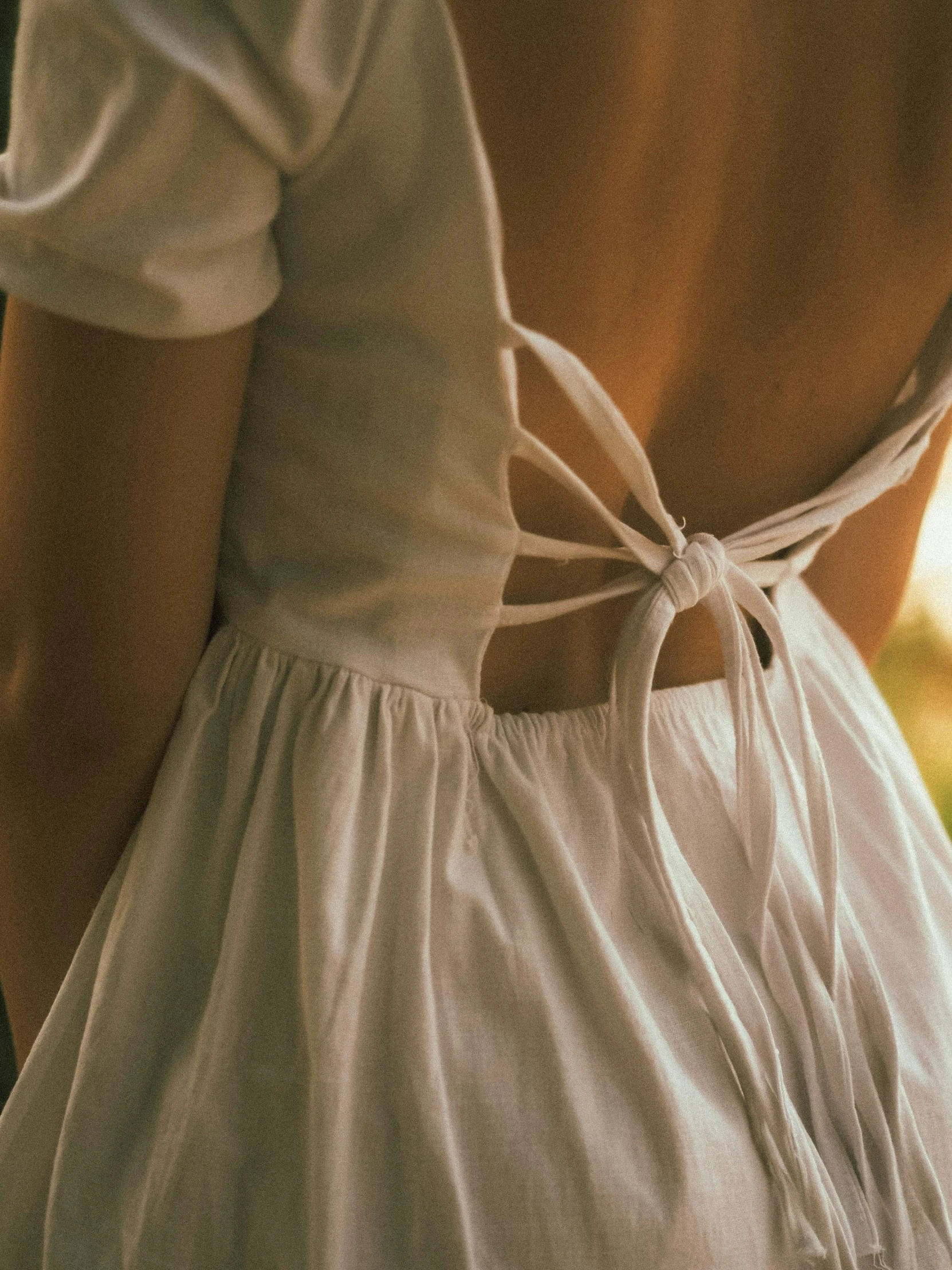 the back of a woman in a white dress, inspired by Nell Dorr, pexels contest winner, renaissance, crop top, trending on vsco, bows, warm glow