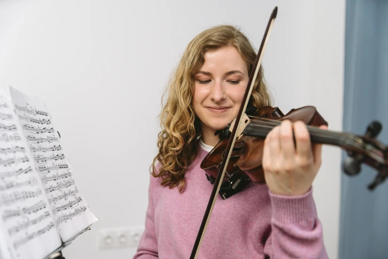 a woman in a pink sweater playing a violin, pexels contest winner, danube school, avatar image, half image