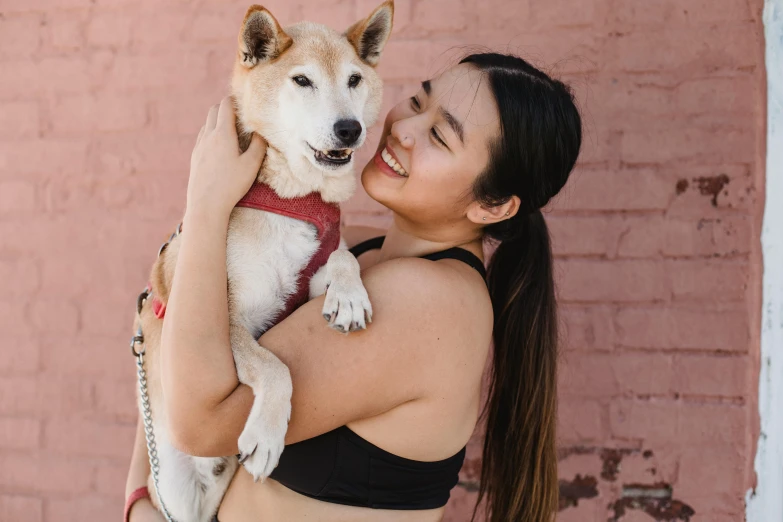 a woman holding a dog in her arms, pexels contest winner, mingei, wearing a crop top, shibu inu, wearing a tanktop, trending on bbwchan