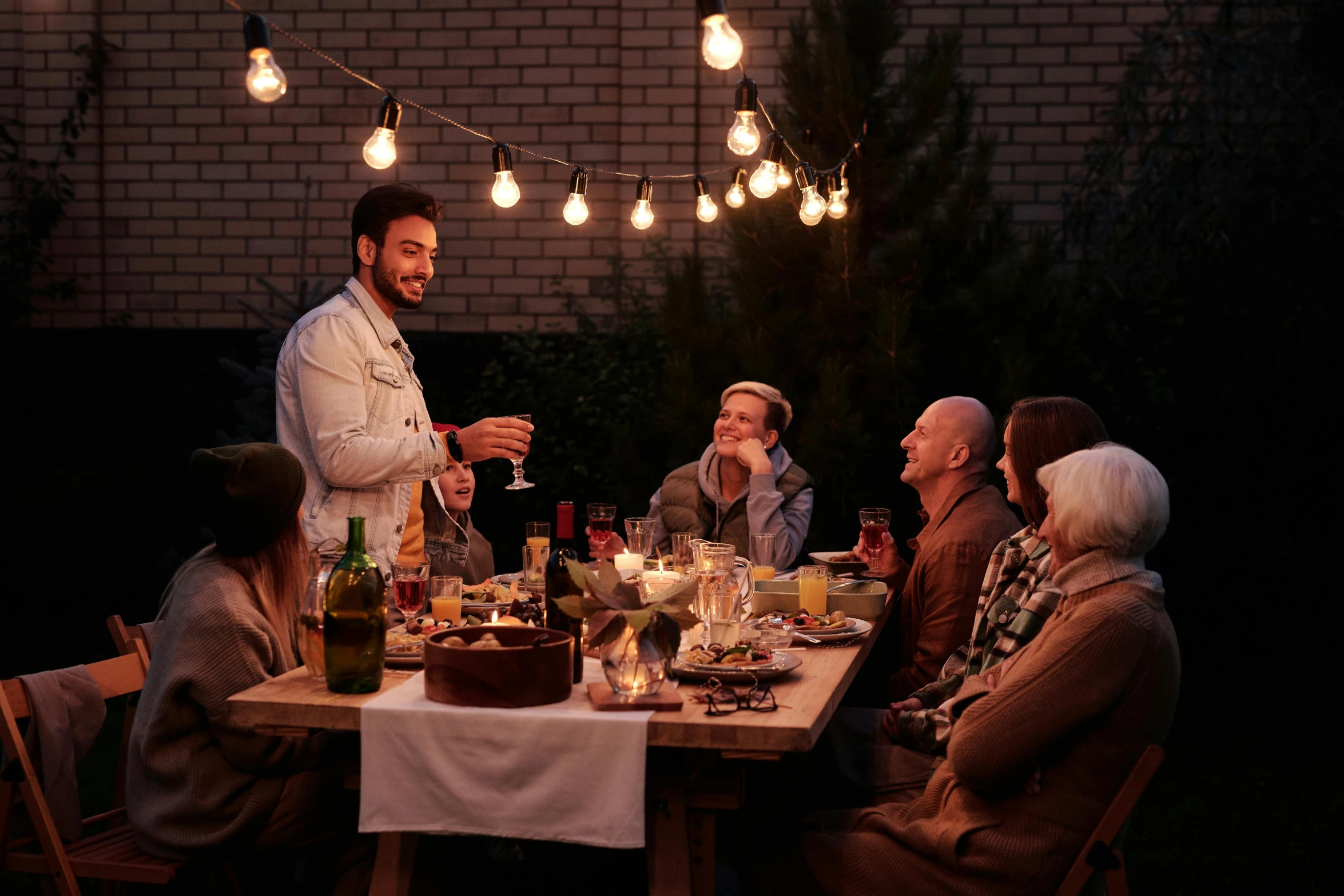 a group of people sitting around a dinner table, outdoor lighting, profile image, rectangle, seasonal