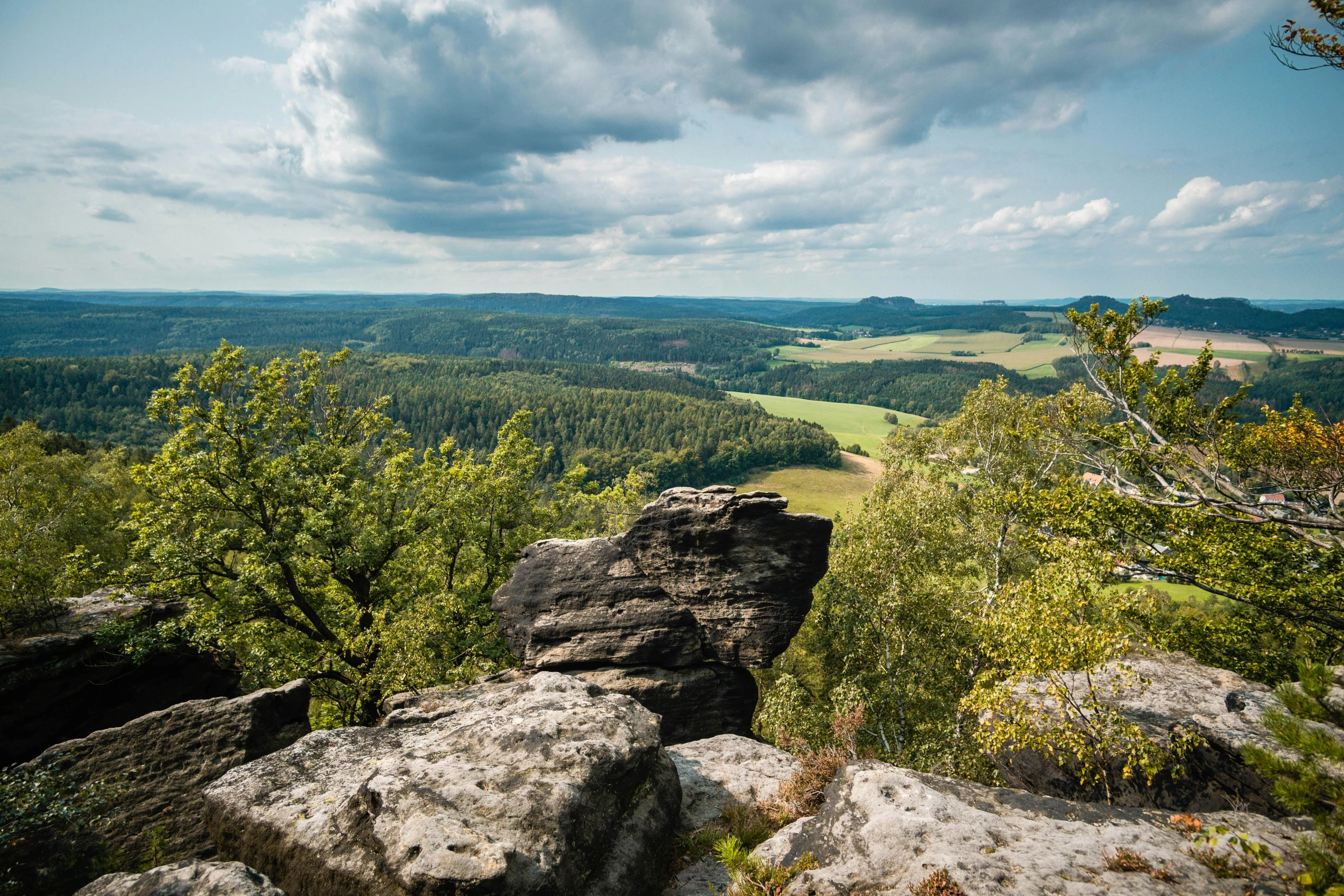 a view of a valley from the top of a mountain, pexels contest winner, german romanticism, tall big rocks, avatar image, lower saxony, lush forest in background