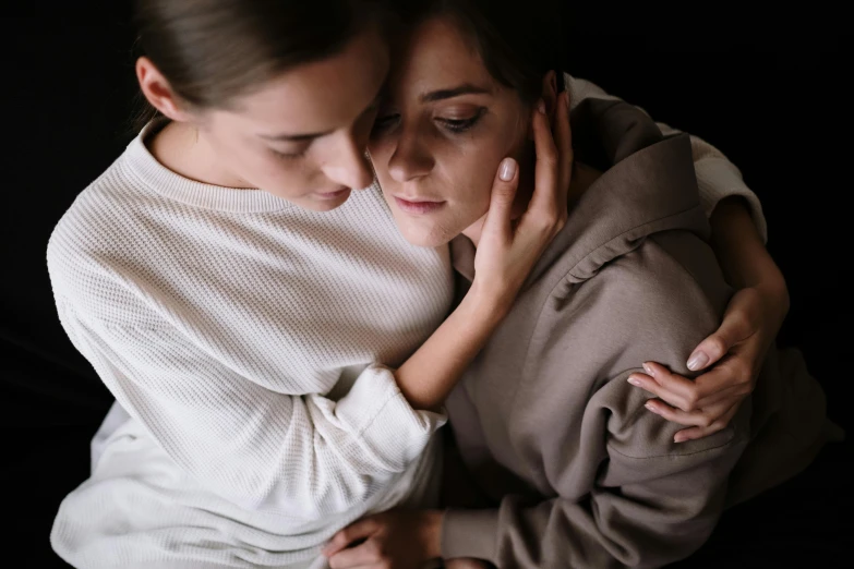 a couple of women that are hugging each other, trending on pexels, white ribbon, looking sad, lesbian, late night