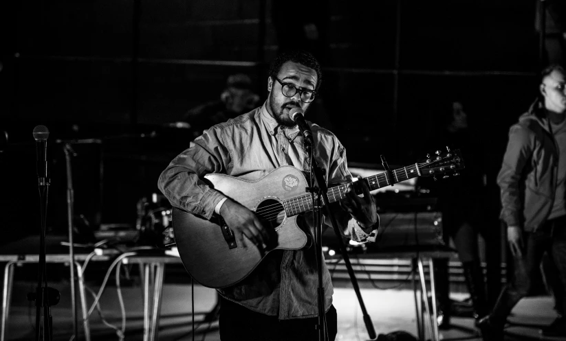 a black and white photo of a man playing a guitar, olafur eliasson, singer songwriter, live performance, iain mccaig