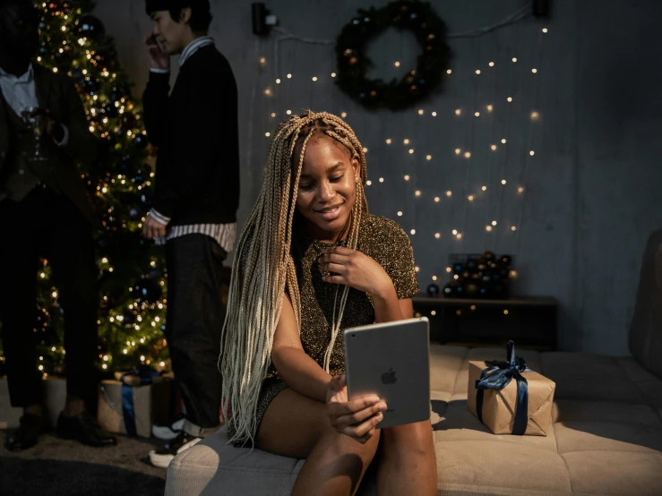 a woman sitting on a couch in front of a christmas tree, a portrait, pexels contest winner, happening, using a magical tablet, black young woman, “house music rave with dancers, a blond