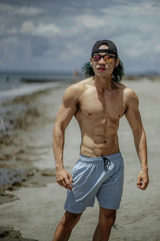 a man riding a skateboard on top of a sandy beach, by Adam Dario Keel, showing off his muscles, david luong, halfbody headshot, wearing sunglasses and a cap