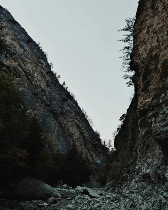 a couple of people standing on top of a rocky mountain, inside a gorge, trending photo, low quality footage, narrow passage