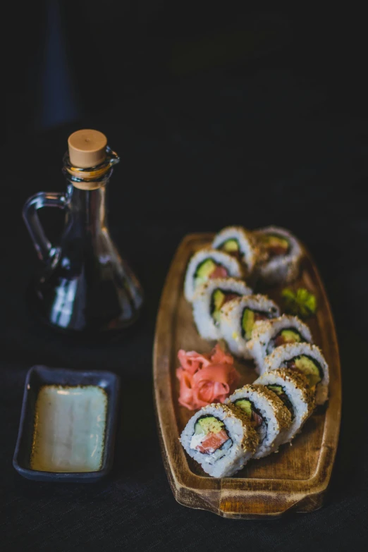 a wooden plate topped with sushi next to a bottle of sauce, unsplash, portrait photo, middle eastern, cold light, 6 pack