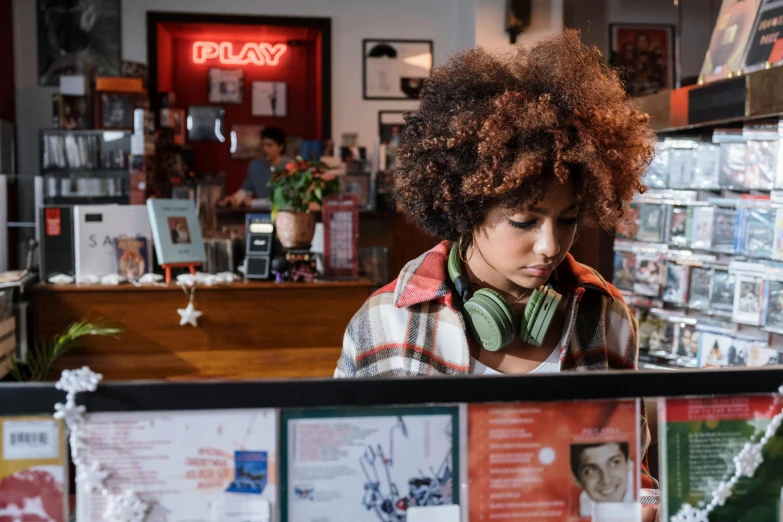 a woman wearing headphones in a music store, happening, curly afro, perfectly lit. movie still, in a coffee shop, official store photo