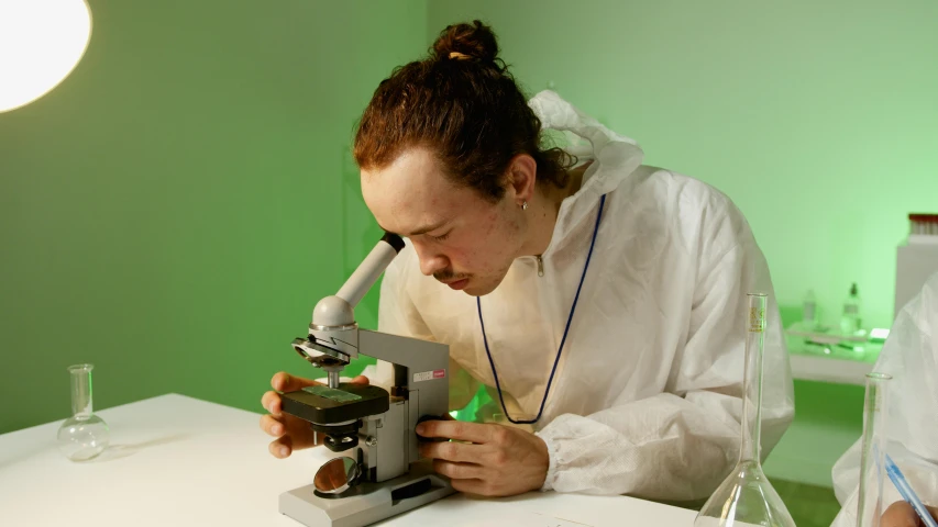 a man in a lab coat looking through a microscope, inspired by Allan Ramsay, hyperrealism, declan mckenna, plating, white, slide show