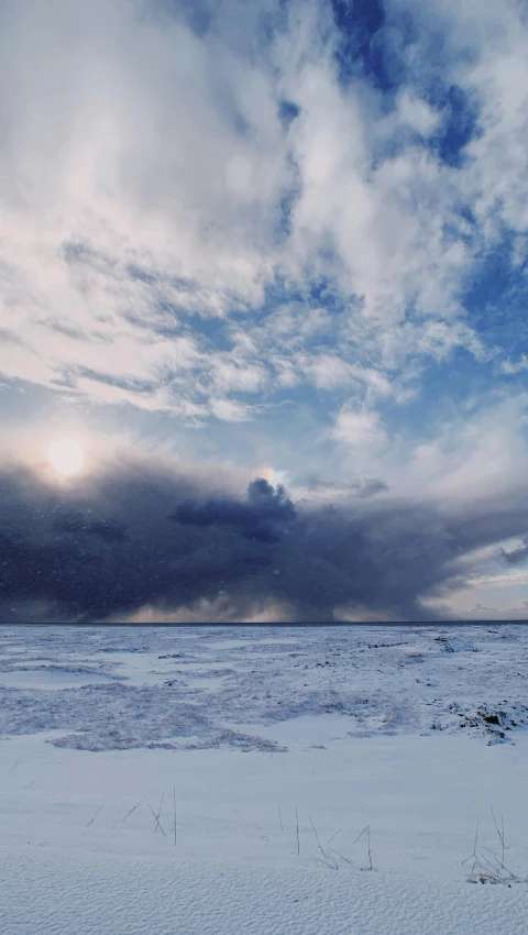 a man riding skis down a snow covered slope, an album cover, unsplash contest winner, land art, big cumulonimbus clouds, icelandic landscape, annie liebowitz, panorama view of the sky