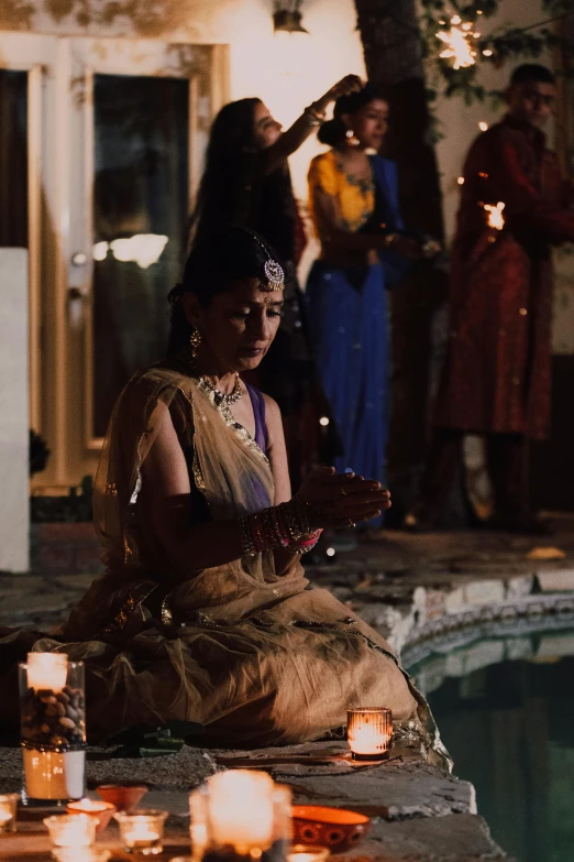 a woman sitting on the edge of a pool surrounded by candles, inspired by Sir William Russell Flint, pexels contest winner, wearing an elegant tribal outfit, film still dnd movie, performance, intricate led jewellery