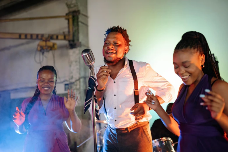 a group of people that are standing in front of a microphone, an album cover, by Chinwe Chukwuogo-Roy, pexels, happening, smiling and dancing, band playing, in the evening, a man