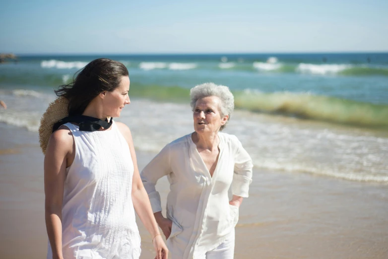 two women walking on the beach holding hands, a portrait, unsplash, older woman, 15081959 21121991 01012000 4k, contemplating, white