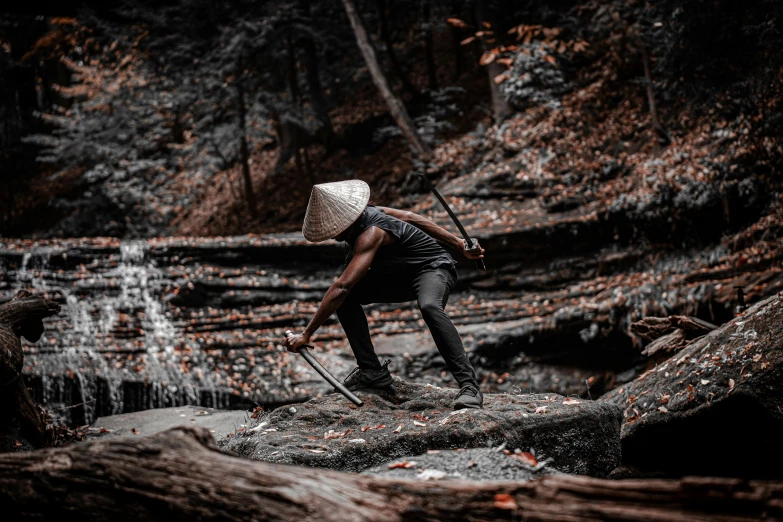 a man standing on top of a rock next to a waterfall, by Alexander Brook, pexels contest winner, afrofuturism, wielding an axe on each hand, woods, white man with black fabric mask, streetwear