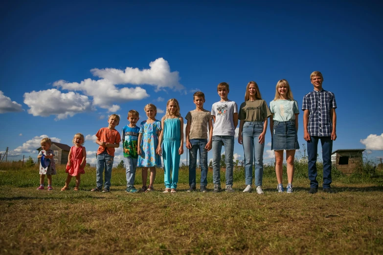 a group of people standing on top of a grass covered field, by The Family Circus, pexels, portrait image, stålenhag, in a row, boys and girls