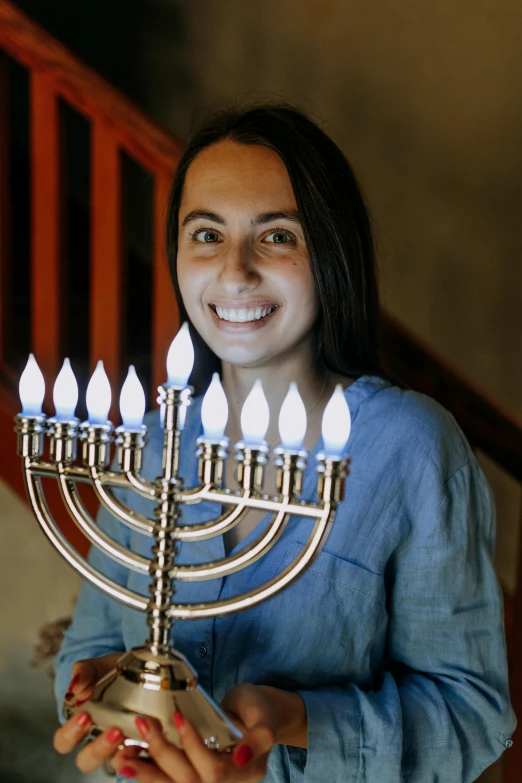 a woman is smiling while holding a menorah, multiple stories, teenager, adafruit, ana de la reguera portrait