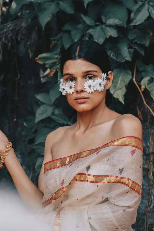 a woman with white flowers on her face, an album cover, by Sunil Das, trending on pexels, wearing toga, at a fashion shoot, chamomile, madhubani