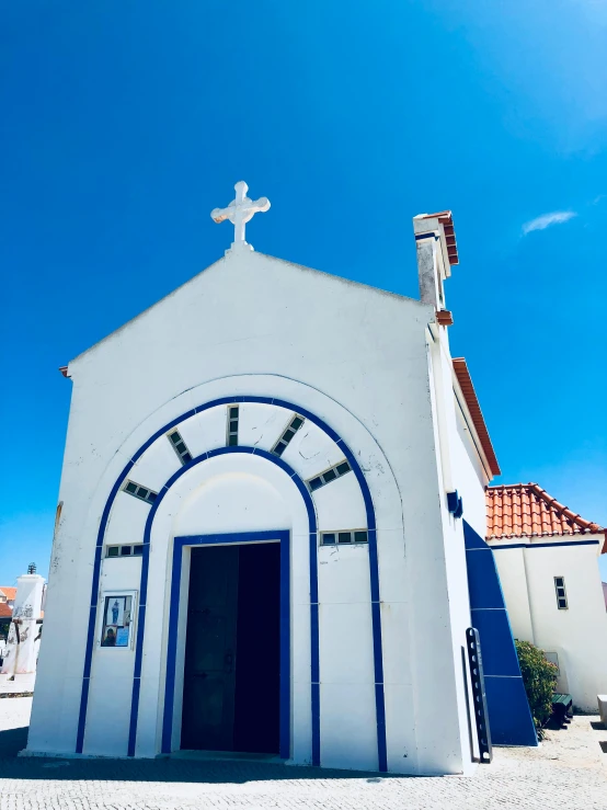 a small white church with a blue door, unsplash, nazare (portugal), 👰 🏇 ❌ 🍃, profile image, gopro photo