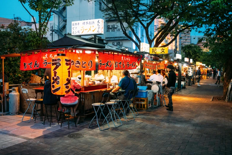 a group of people sitting at a food stand, a photo, by Julia Pishtar, pexels contest winner, ukiyo-e, city lights made of lush trees, neon signs in background, square, sake