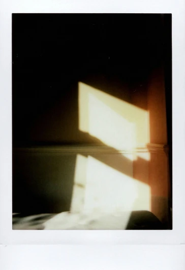 a white bed sitting under a window next to a wall, a polaroid photo, by Nathalie Rattner, conceptual art, sun shafts, ( ( photograph ) ), refracted light, dramatic lighting - n 9