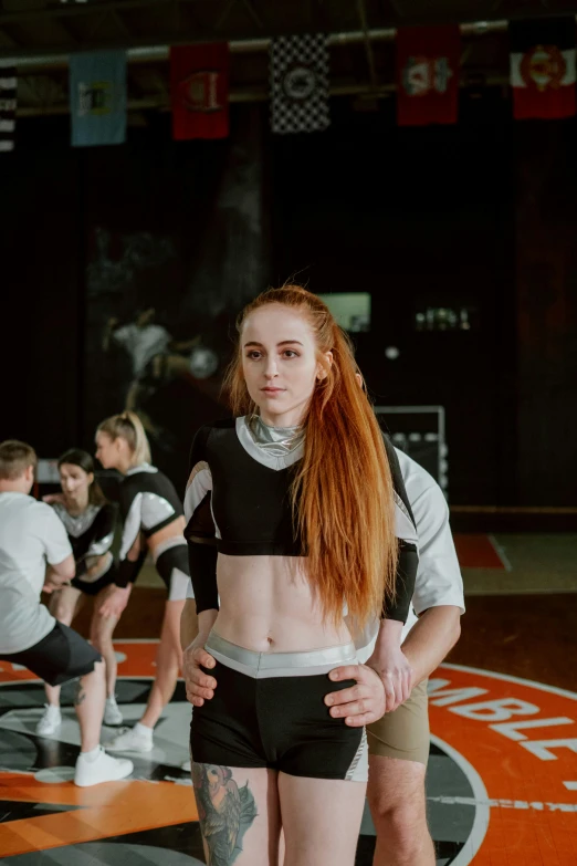 a woman standing on top of a basketball court, by Emma Andijewska, white and orange breastplate, wrestling, low quality photograph, lachlan bailey