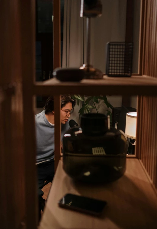 a man sitting on a couch in a living room, pexels contest winner, hyperrealism, japanese collection product, holding up a night lamp, spying discretly, shelf