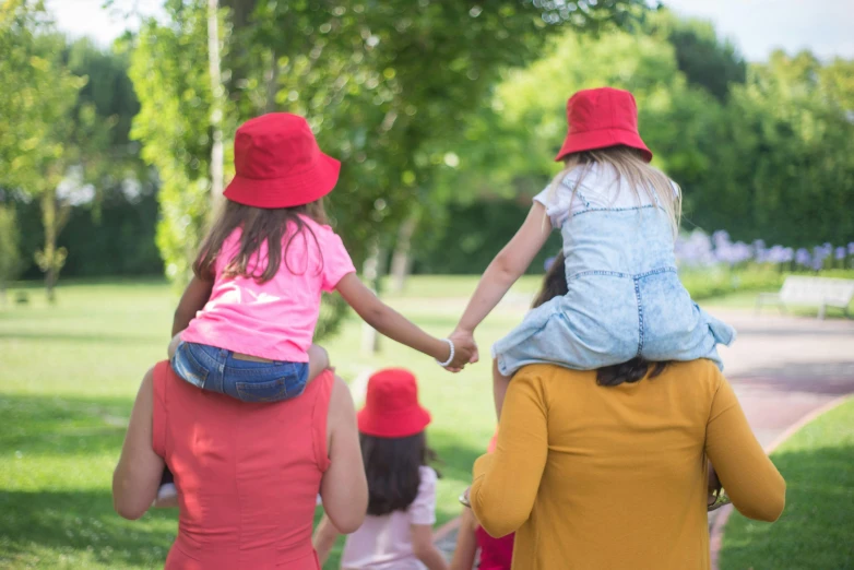 a little girl riding on the back of a woman's shoulders, inspired by The Family Circus, pexels contest winner, red ascot and a field cap, of a family standing in a park, holding each other hands, wearing wide sunhat