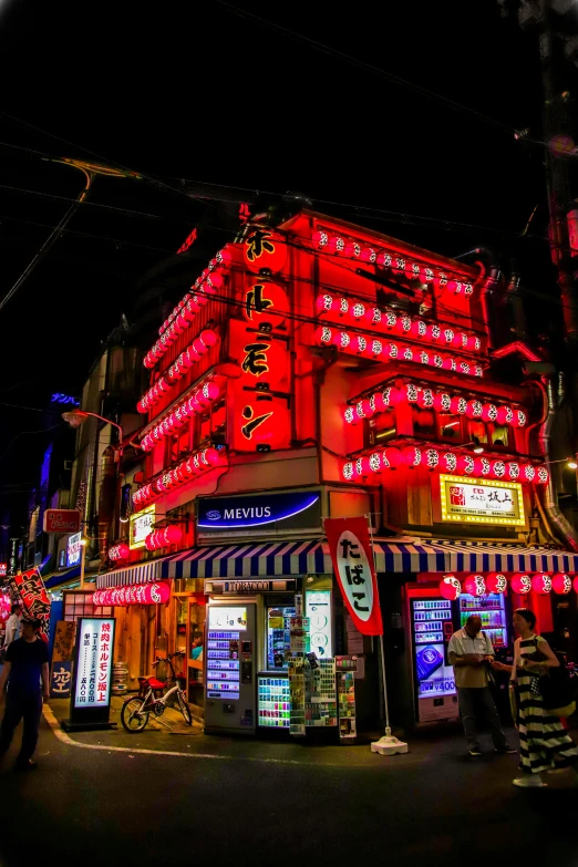 a group of people standing in front of a building, inspired by Tadanori Yokoo, pexels, neon lights above shops, red roofs, dive bar with a karaoke machine, japan. volumetric lighting