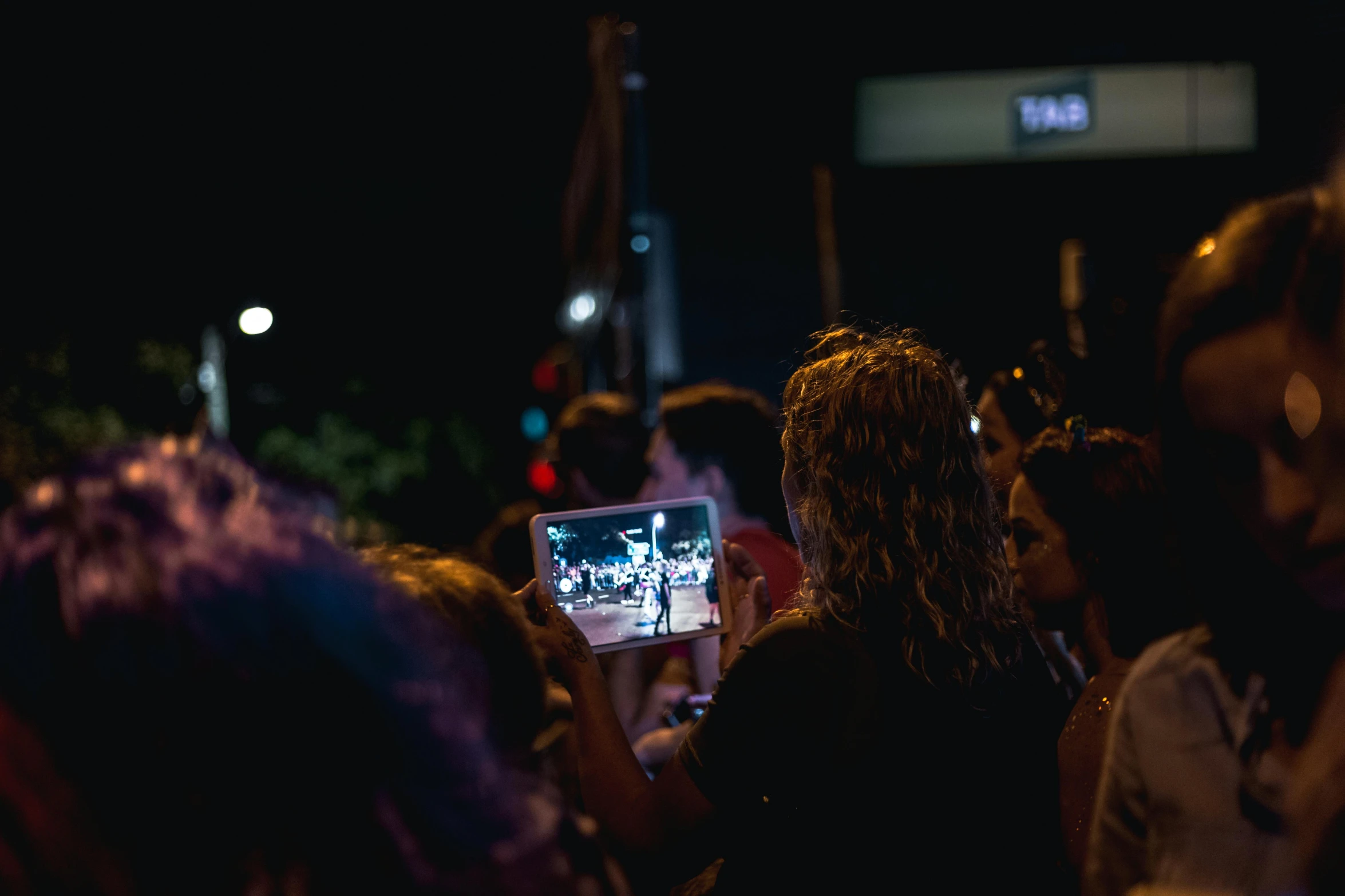 a group of people standing next to each other at night, crowds, facing away from the camera, taking a selfie, performing