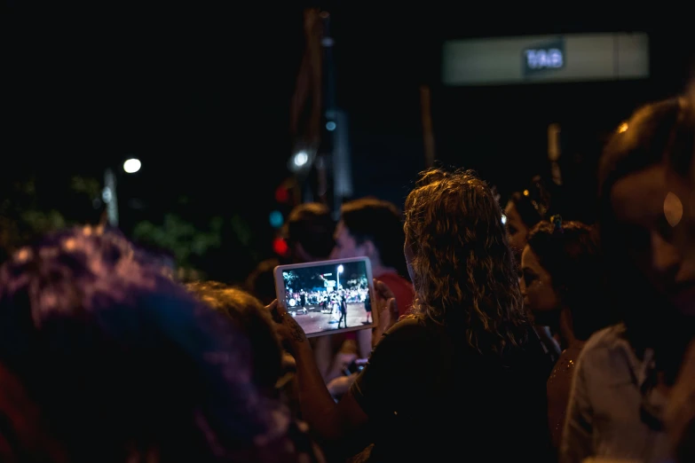 a group of people standing next to each other at night, crowds, facing away from the camera, taking a selfie, performing