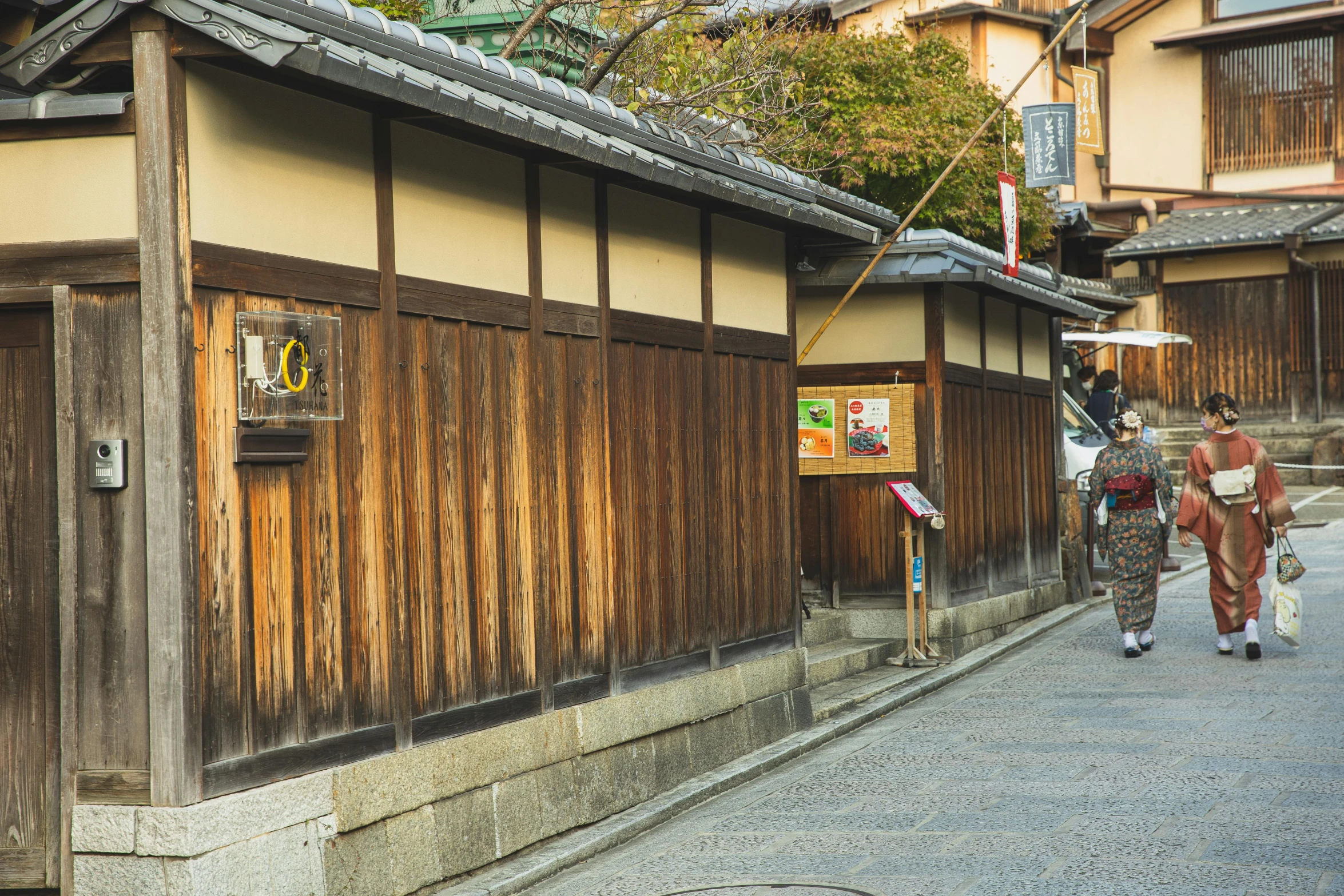 a couple of people walking down a street, inspired by Kaii Higashiyama, pexels contest winner, ukiyo-e, wooden structures, shop front, 2 0 0 0's photo, exterior view