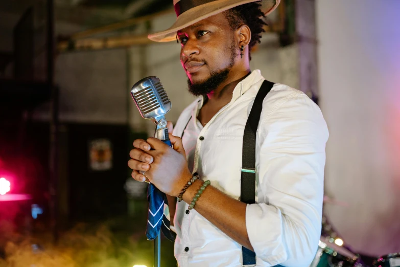 a man in a hat holding a microphone, muzinabu, profile image, photoshoot, rectangle