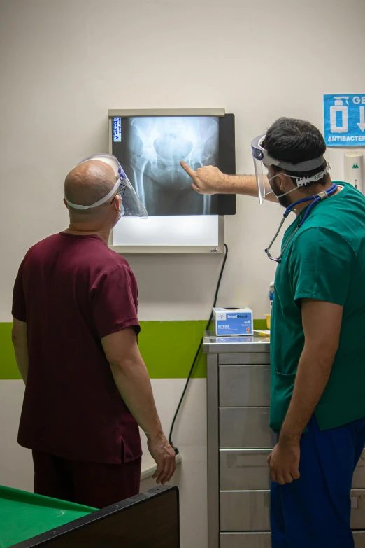 a couple of men standing next to each other in a room, a picture, surgical impliments, in spain, rear facing, mid - action